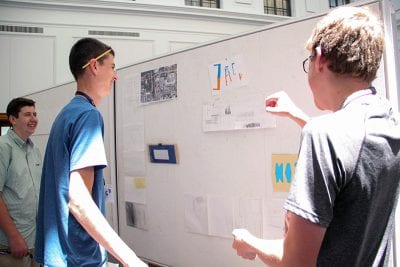 Students pin up their work for the final review and reception held June 15.